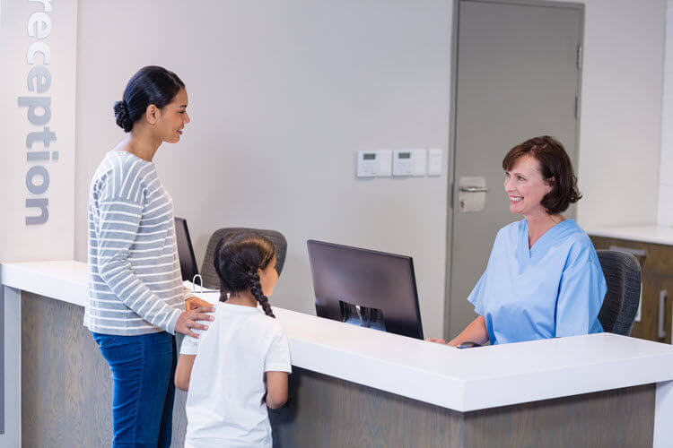 A woman and her daughter forming their first impressions in healthcare at the reception desk.